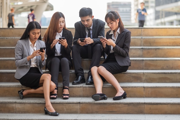 Close up group of business people relaxing using smart phone in the city