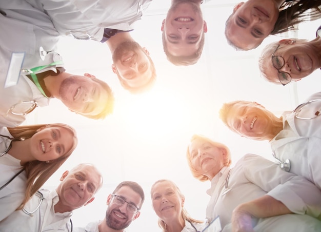 Close up group of doctors standing in a circle and looking at you