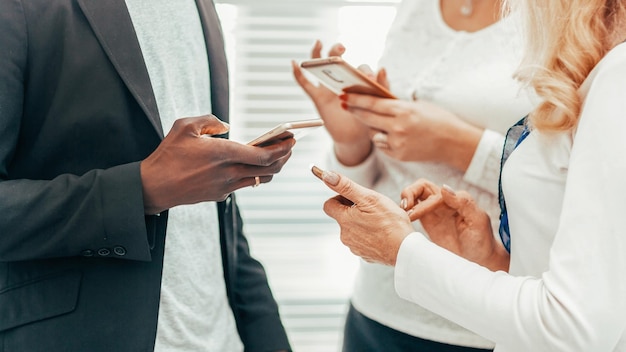 Close up. a group of employees with interest watching the video on their smartphone.