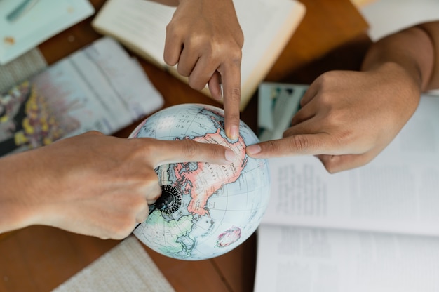 Close up group of people point a finger on globe