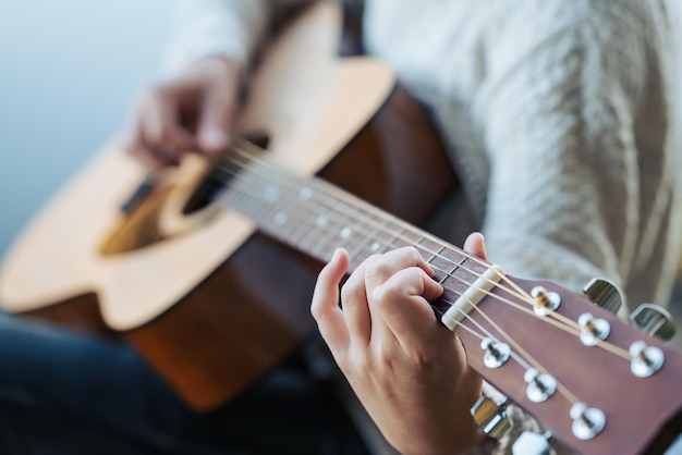 Close up of guitar in hands of a girl Playing music in nature near water space enjoying young life years relaxing and having a good time