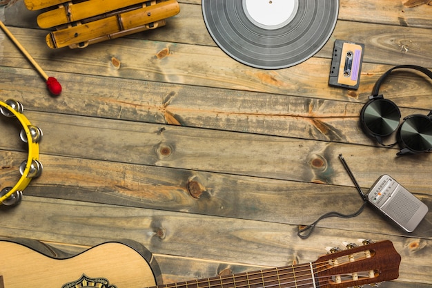 Close-up of guitar; headphone; tambourine; xylophone; headphone and radio on wooden table