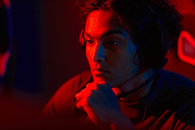 Close-up of hacker in headphones concentrating on his work sitting in dark room