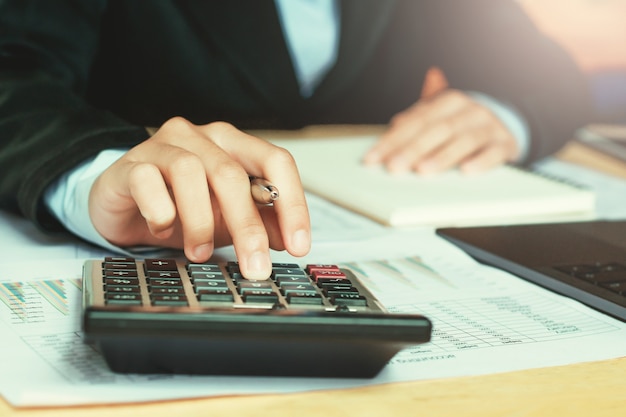 close up hand accountant using calculator with laptop