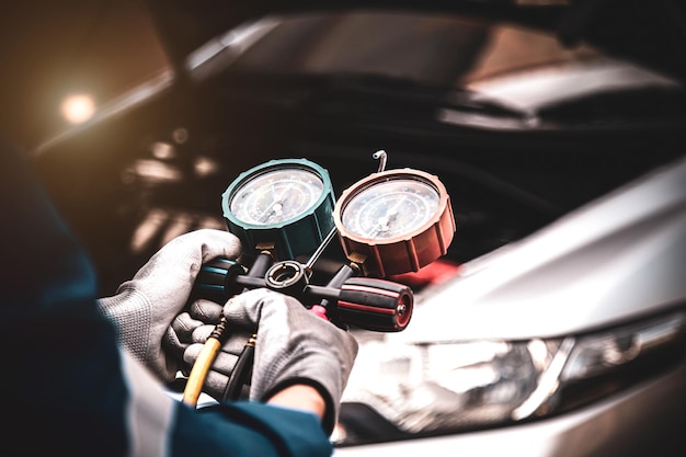 Close up hand of auto mechanic using measuring manifold gauge check the refrigerant and filling car air conditioner for fix and checking for repair service support maintenance and car insurance