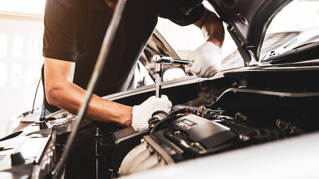 Close-up hand of auto mechanic using wrench to repair a car engine.