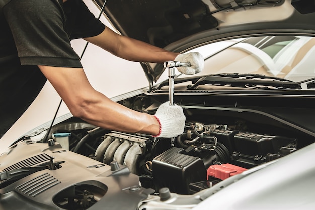 Close-up hand of auto mechanic using wrench to repair a car engine.