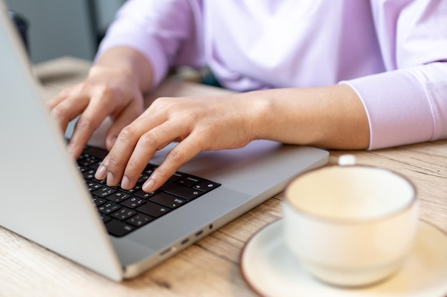 Close up hand of a business woman typing keyboard laptop computer on desk office