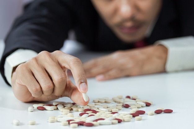 Close-up of hand businessperson holding pills in stress from overworked in workspace blurred. Concept of failure working