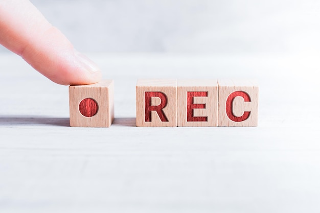 Photo close-up of hand by toy block with rec text on table