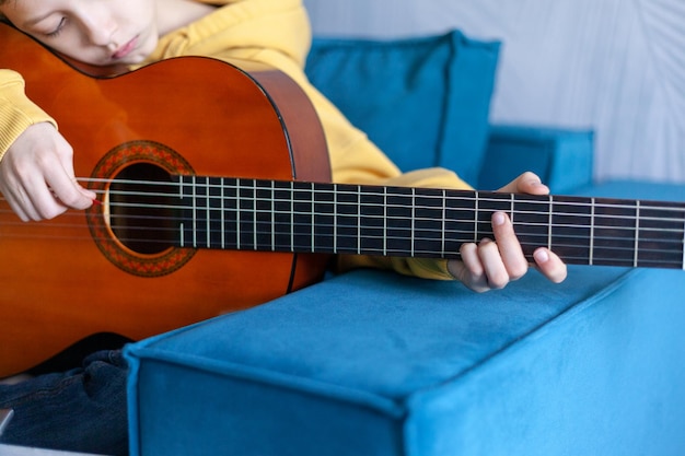 Close up hand of child playing acoustic guitar Cute boy is playing guitar in his room at home