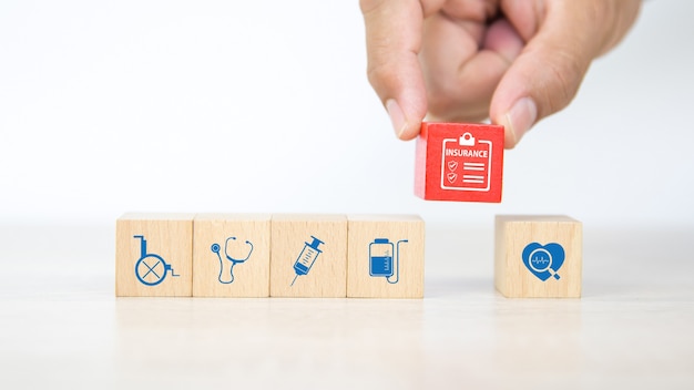 Close-up hand choose wooden block with insurance icon.