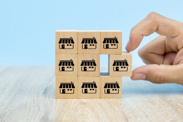 Close-up hand choosing wooden block stack with franchise icon.