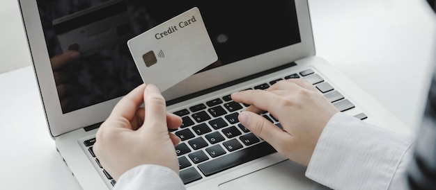 Close up hand entering password code on laptop computer paying bill with credit card on desk at home office, internet, digital marketing, shopping online, online payment and digital technology concept