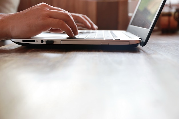 close up hand and finger typing laptop keyboard on wooden table with copy space