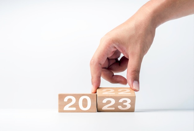 Close up hand flipping the 2022 to 2023 year numbers calendar on wooden cube blocks for preparation the new year change begin and start new business target strategy and happy new year 2023 concept