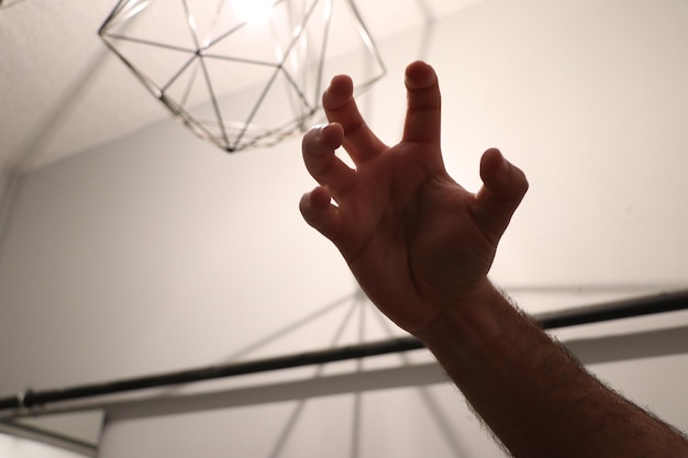 Photo close-up of hand gesturing against ceiling