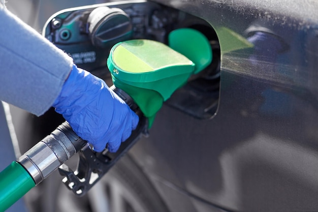 Photo close up of hand in glove filling car with petrol