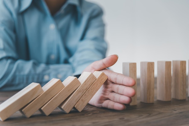 Photo close-up hand the hand of a businessman who is stopping or preventing a falling block.risk protection concept,eliminating the risk