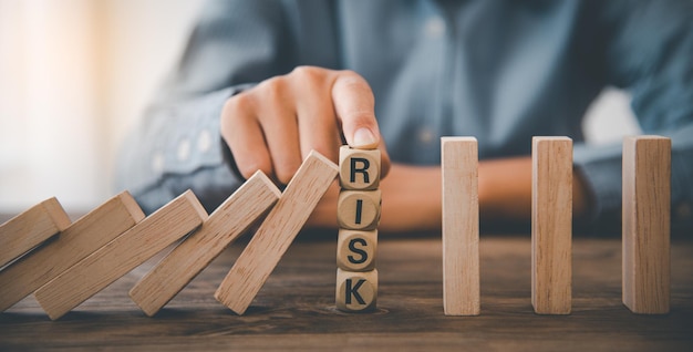 Close-up hand The hand of a businessman who is stopping or preventing a falling block.Risk protection concept,Eliminating the risk