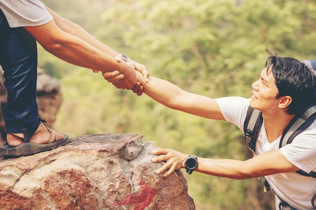 Close up of hand helping each other hike up a mountain Help and support concept