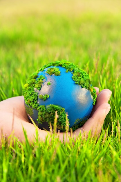 Close-up of hand holding artificial planet earth on grass