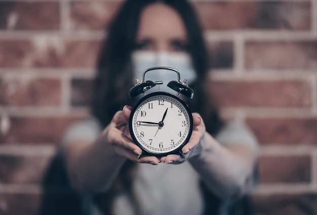 Close-up of hand holding clock against blurred background