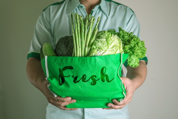 Close up hand holding green grocery bag of mixed the organic green vegetables , healthy organic green food shopping and diet healthcare nutrition therapy 