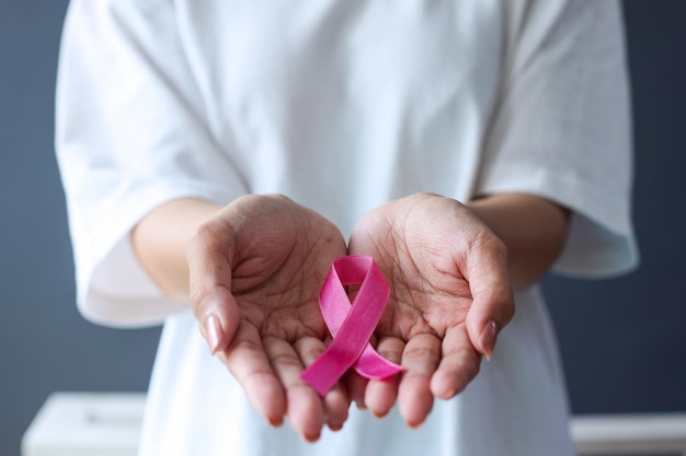 Close up hand holding pink ribbon Breast cancer awareness month World Cancer Day