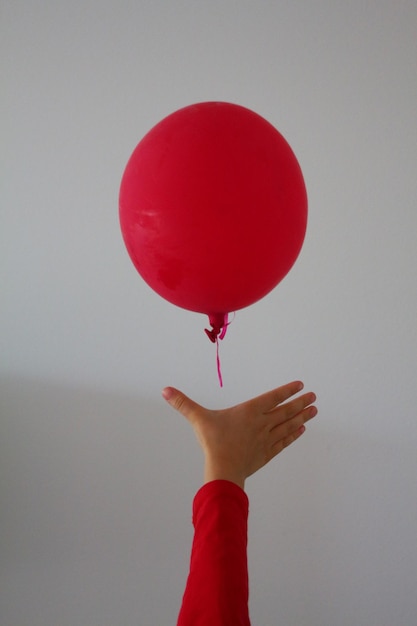 Photo close-up of hand holding red balloons against white background