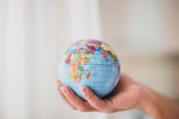 Photo close-up of hand holding small globe