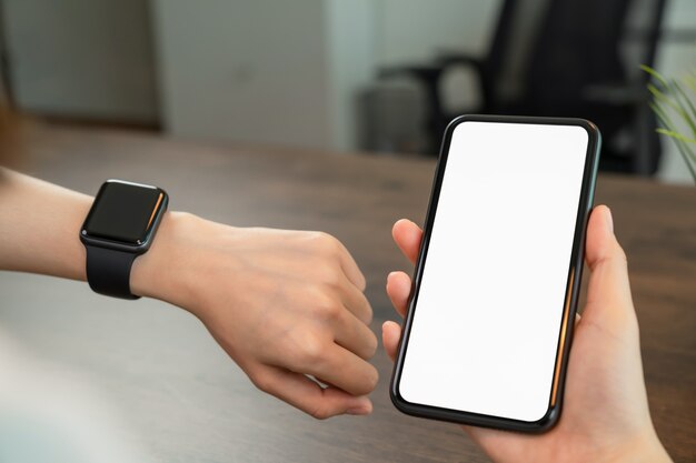 Close-up of hand holding smartphone and looking smartwatch