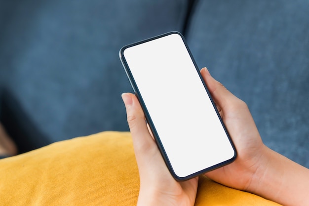 Close up of hand holding smartphone with white mock-up screen.