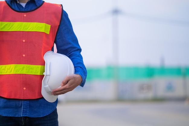 Close up hand holding white helmet hard hat Engineering concept Technician holding hard hat safety hard hat sunlight background