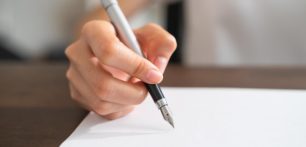 Close up of hand holds pen and signing contract documents paper in office