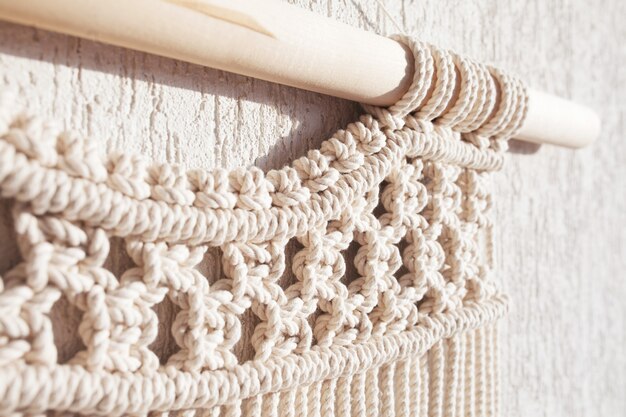 Close-up of hand made macrame texture pattern. ECO friendly modern knitting DIY natural decoration concept  in the interior.  Handmade macrame 100% cotton. Female hobby.