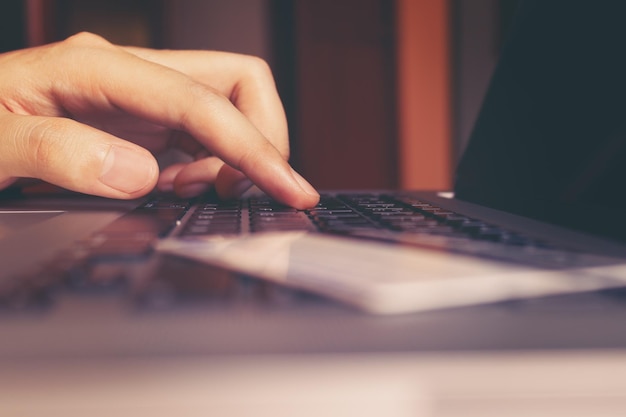 Close up of hand man typing keyboard computer laptop and credit card with shopping online