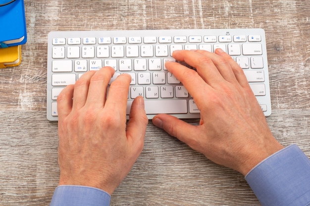 Close up hand of man typing on the white keyboard