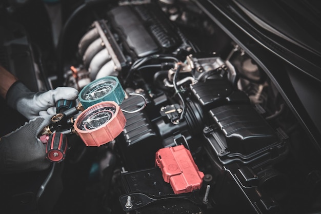 Close up hand of mechanic using manifold gauge check the refrigerant car air conditioner