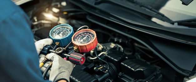 Close up hand of mechanic using manifold gauge check the refrigerant car air conditioner