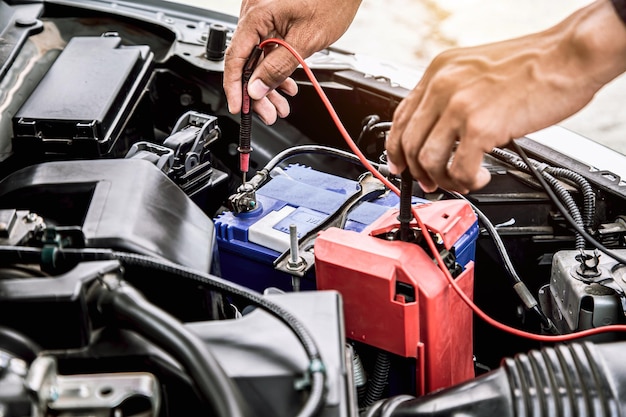 Close up hand of mechanic using measuring checking car battery