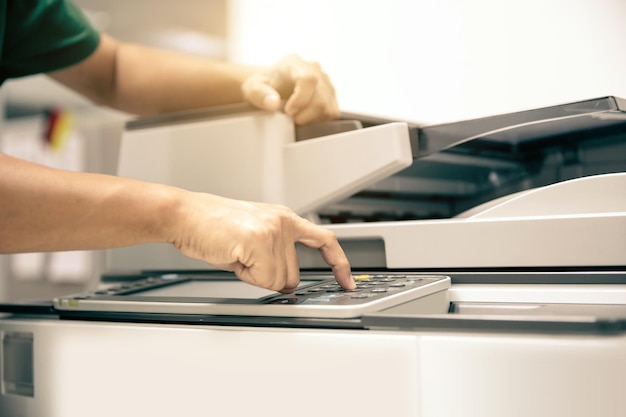 Close up hand office man press copy button on panel to using the photocopier