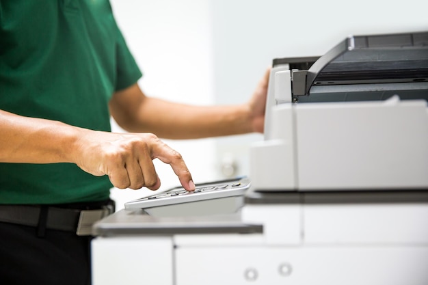 Close up hand office man press copy button on panel to using the photocopier