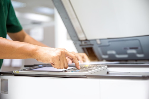 Close up hand office man press copy button on panel to using the photocopier