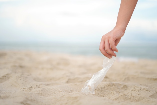 Close up hand pick the plastic bag up from the beach 