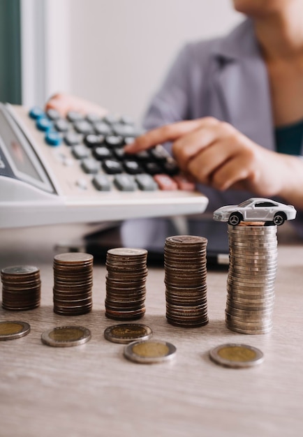 Close up of hand putting coin on pile coins for saving money Collect money to buy a new car saving and car loan concept Flat lay