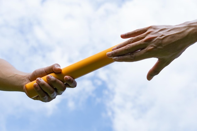 Close up hand set baton from hand to hand on sky background Business concept for teamwork and team builder