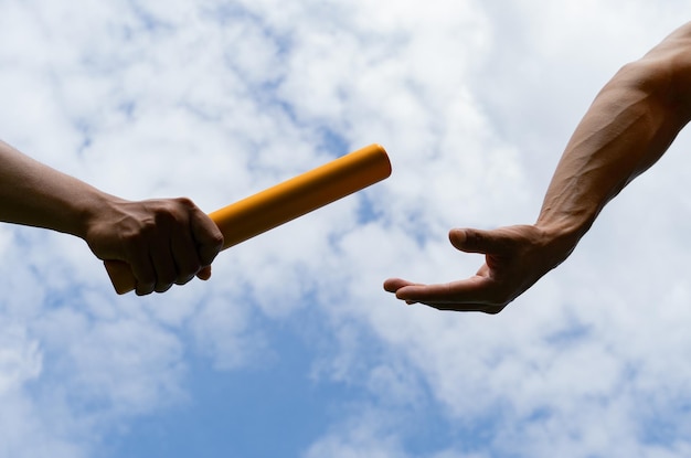 Close up hand set baton from hand to hand on sky background Business concept for teamwork and team builder