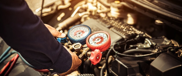 Close up hand of technician using manifold gauge to filling car air conditioners.