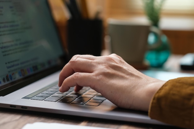 Close up hand typing on laptop keyboard when woking at home